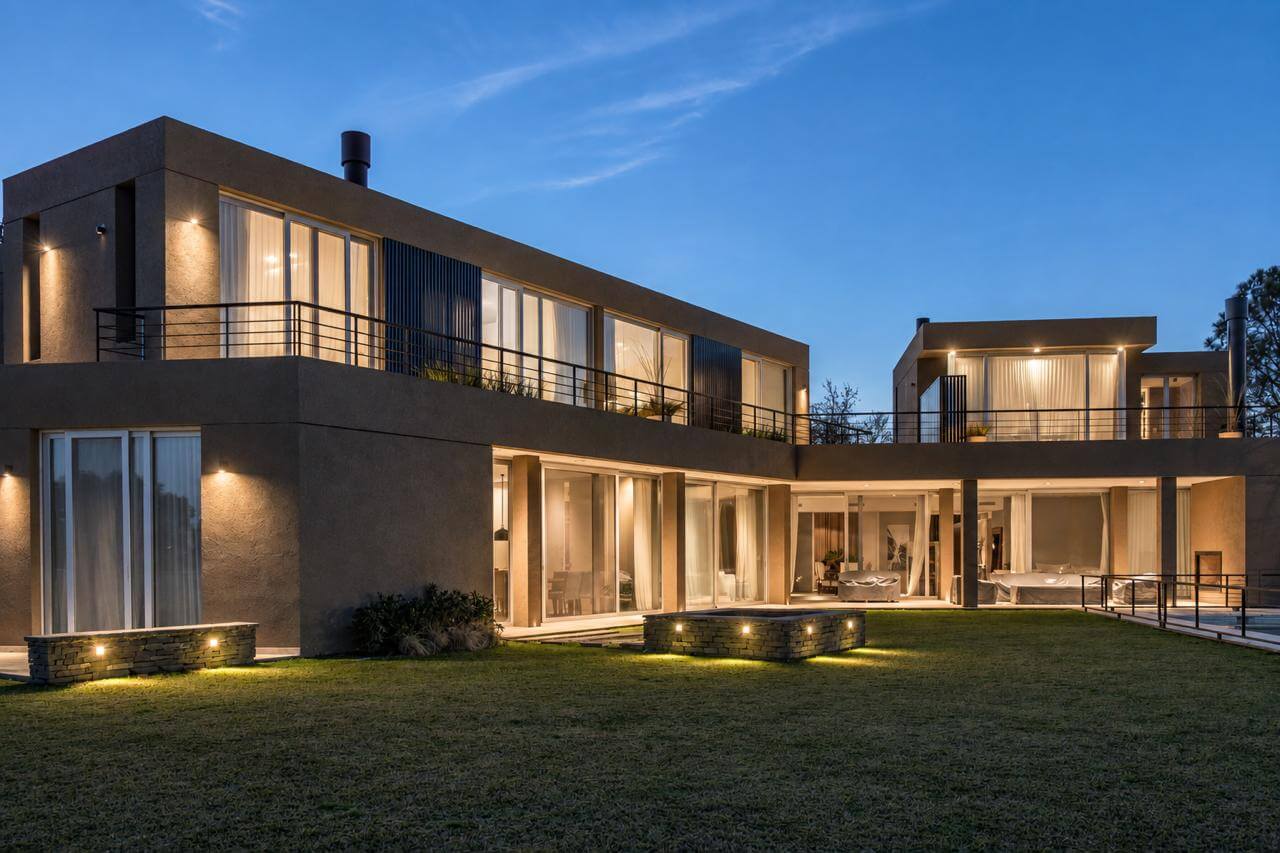 Casa CUBA al anochecer, con iluminación cálida en fachada y jardín